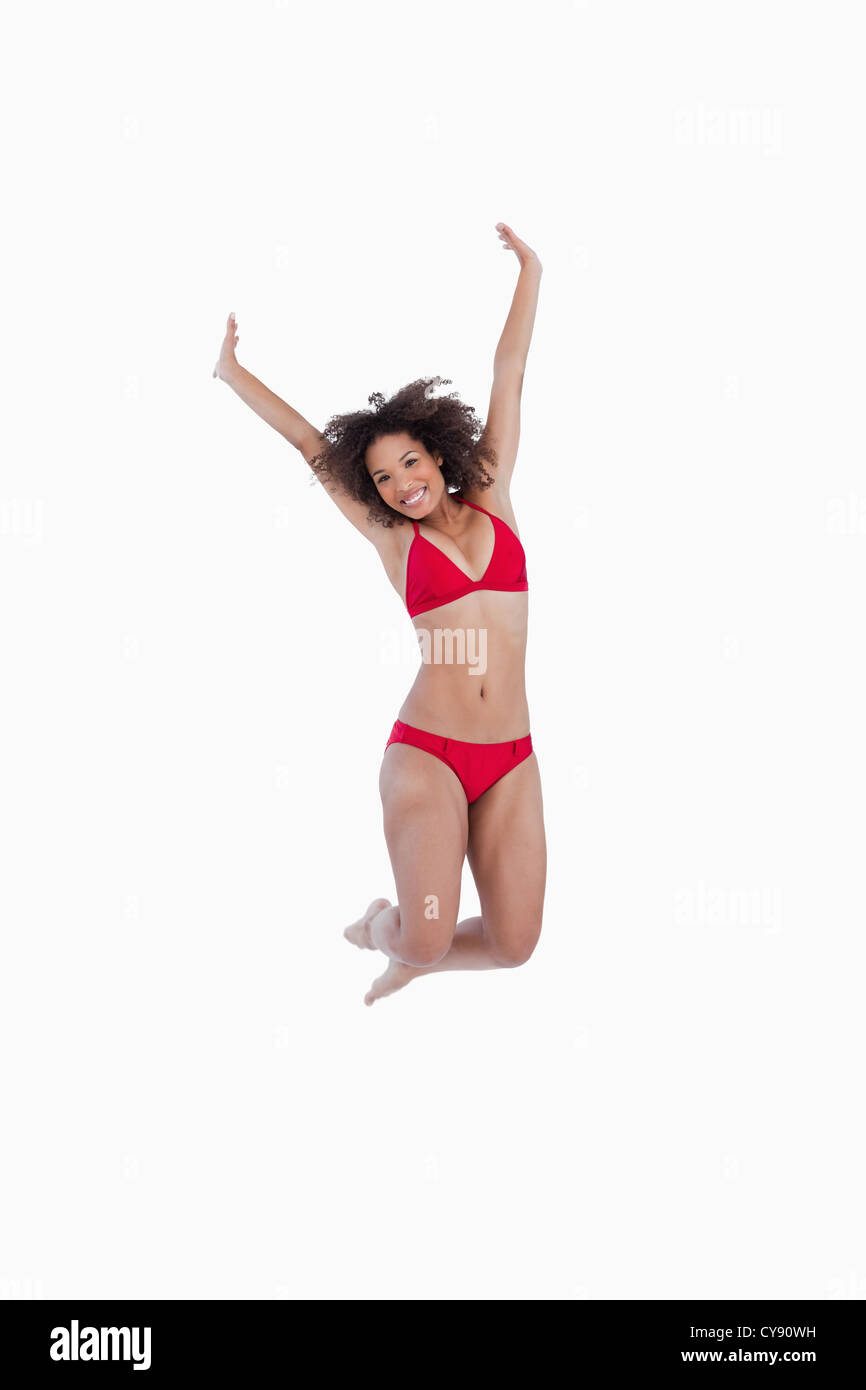 Smiling brunette jumping while raising her arms Stock Photo