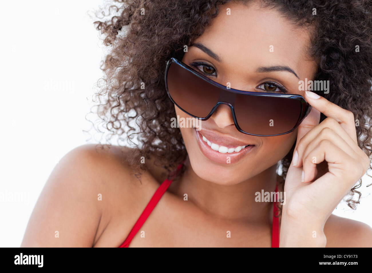 Smiling young brunette looking over her sunglasses Stock Photo
