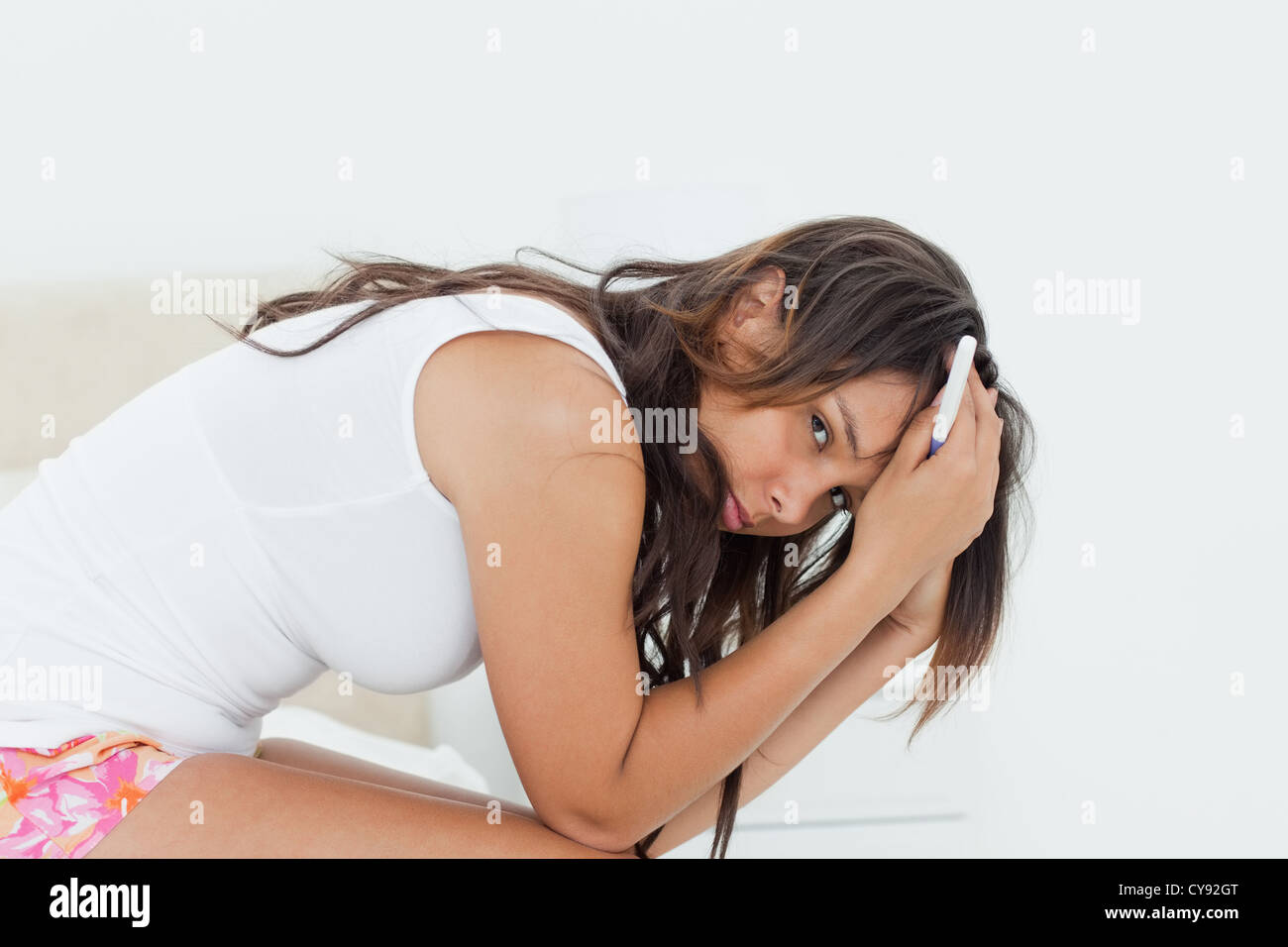 Sad young woman holding a pregnancy test Stock Photo