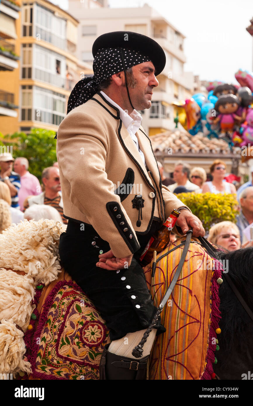 Spanish rider in a Religious Procession with beer bottle in saddle