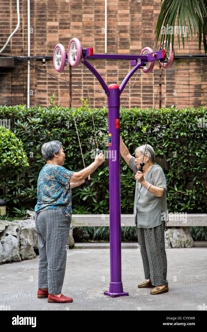 Elderly Chinese women exercise on a machine in the old French Concession of Shanghai, China Stock Photo