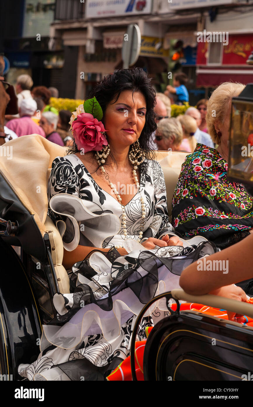 Spanish lady rides in a carriage dressed in Spanish dress. Religious