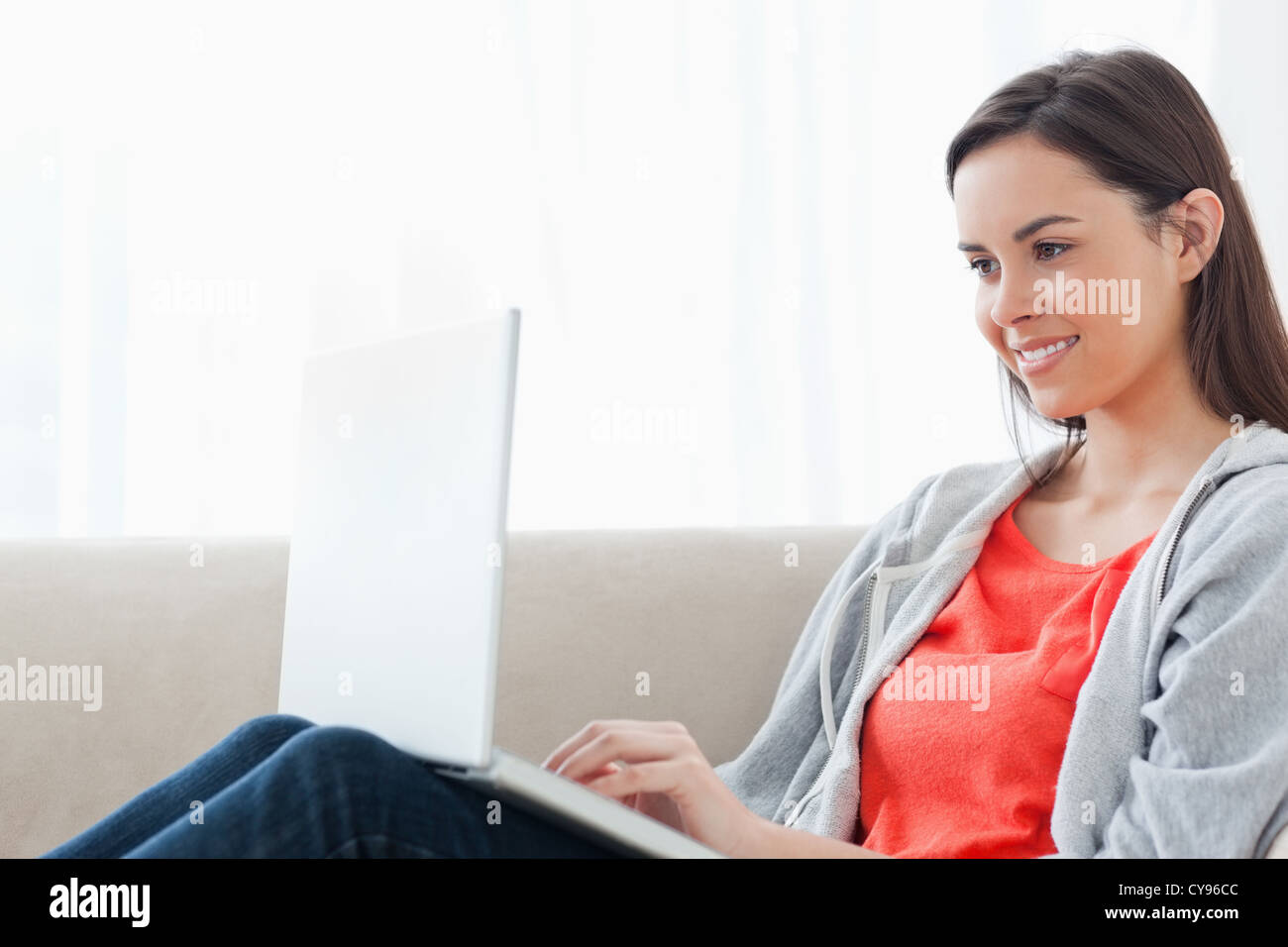 A woman lying on the couch smiling with her laptop Stock Photo - Alamy