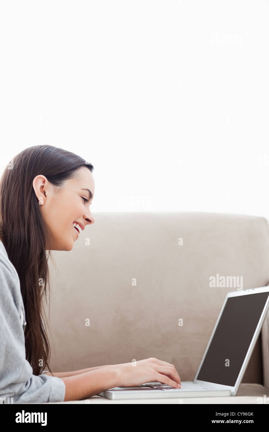 A laughing woman lying on her couch with her laptop Stock Photo - Alamy