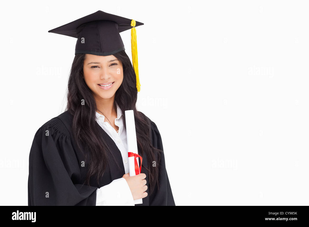 A woman standing to the side slightly with her degree and dressed in her graduation robe Stock Photo