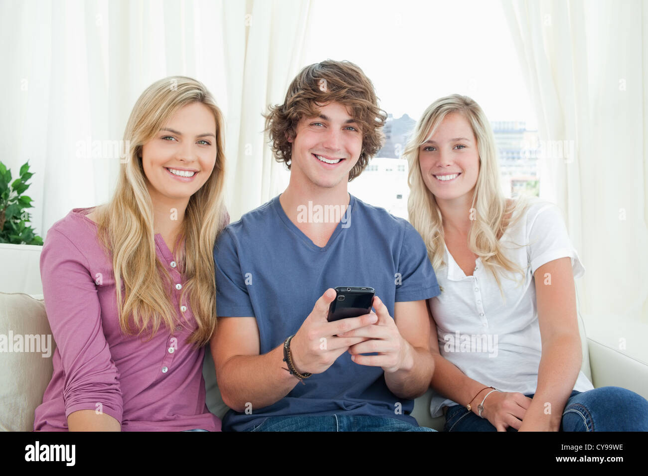 Three friends sitting together looking at the camera Stock Photo - Alamy