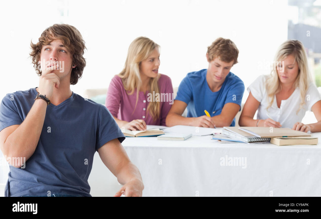 A young man sitting in front of his working class mates and thinking Stock Photo