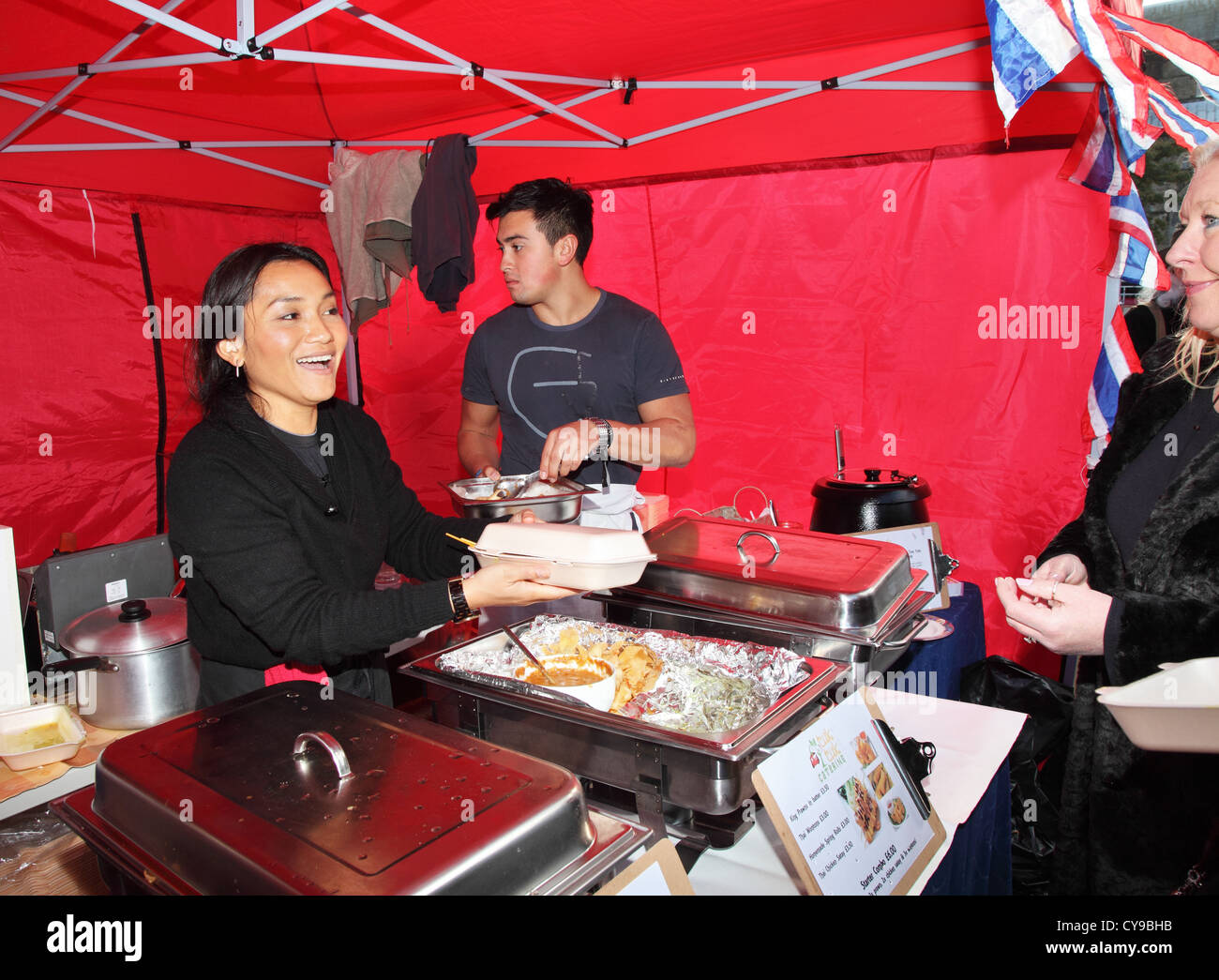 Smiling Asian woman serves Thai food to a customer at Durham City food festival, north east England, UKfoo Stock Photo