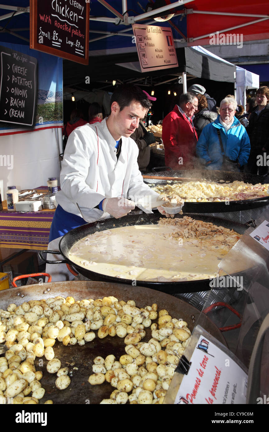 Italian man serving roasted potatoes and creamy chicken Durham City food festival, north east England, UK Stock Photo