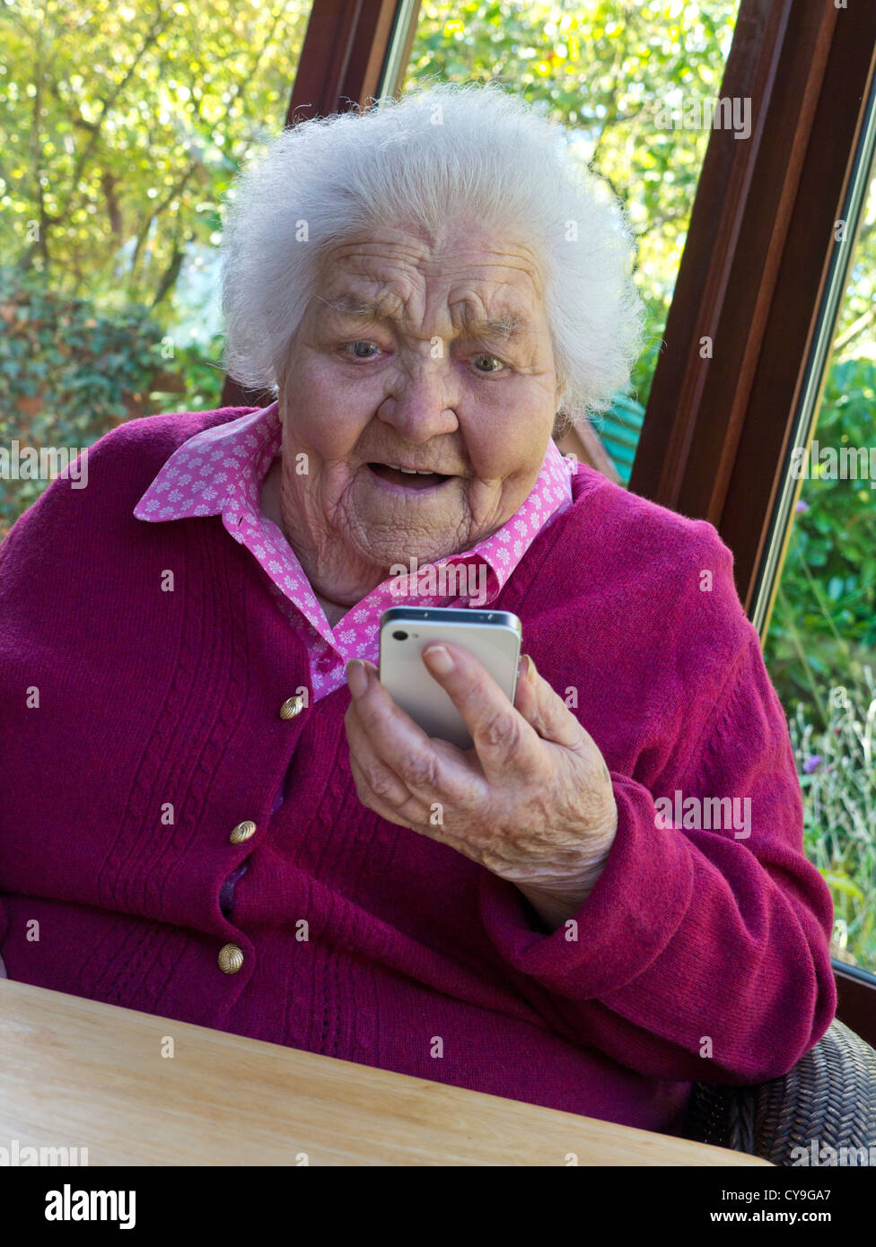 Elderly old lady on her iPhone smartphone senior at home enjoying safe new technology family & friends FaceTime Video Call technology mobile phone Stock Photo