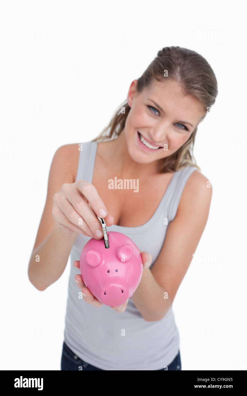 Portrait of a smiling woman putting a note in a piggy bank Stock Photo ...