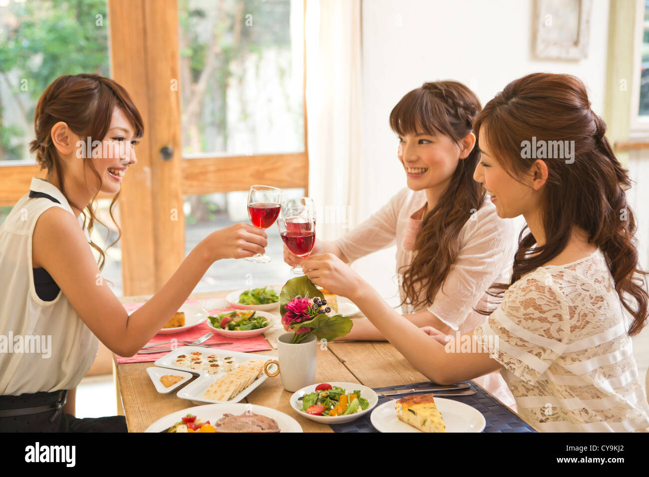 Three Young Women Toasting with Wine Stock Photo