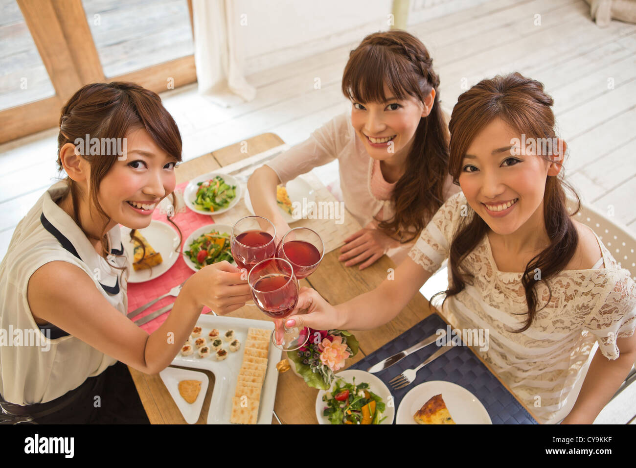 Three Young Women Toasting with Wine Stock Photo