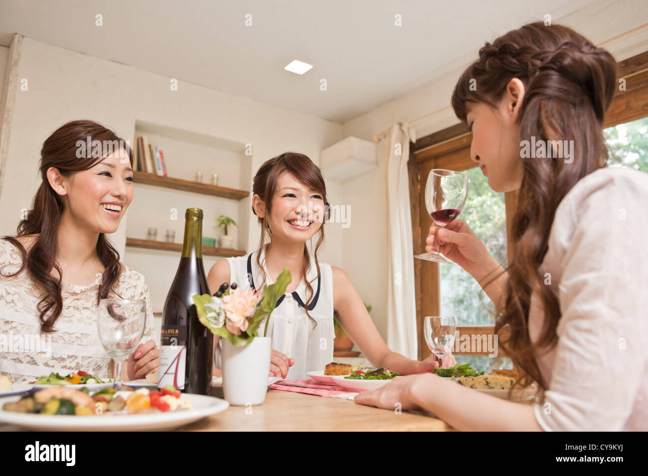 Three Young Women Enjoying Wine at Party Stock Photo