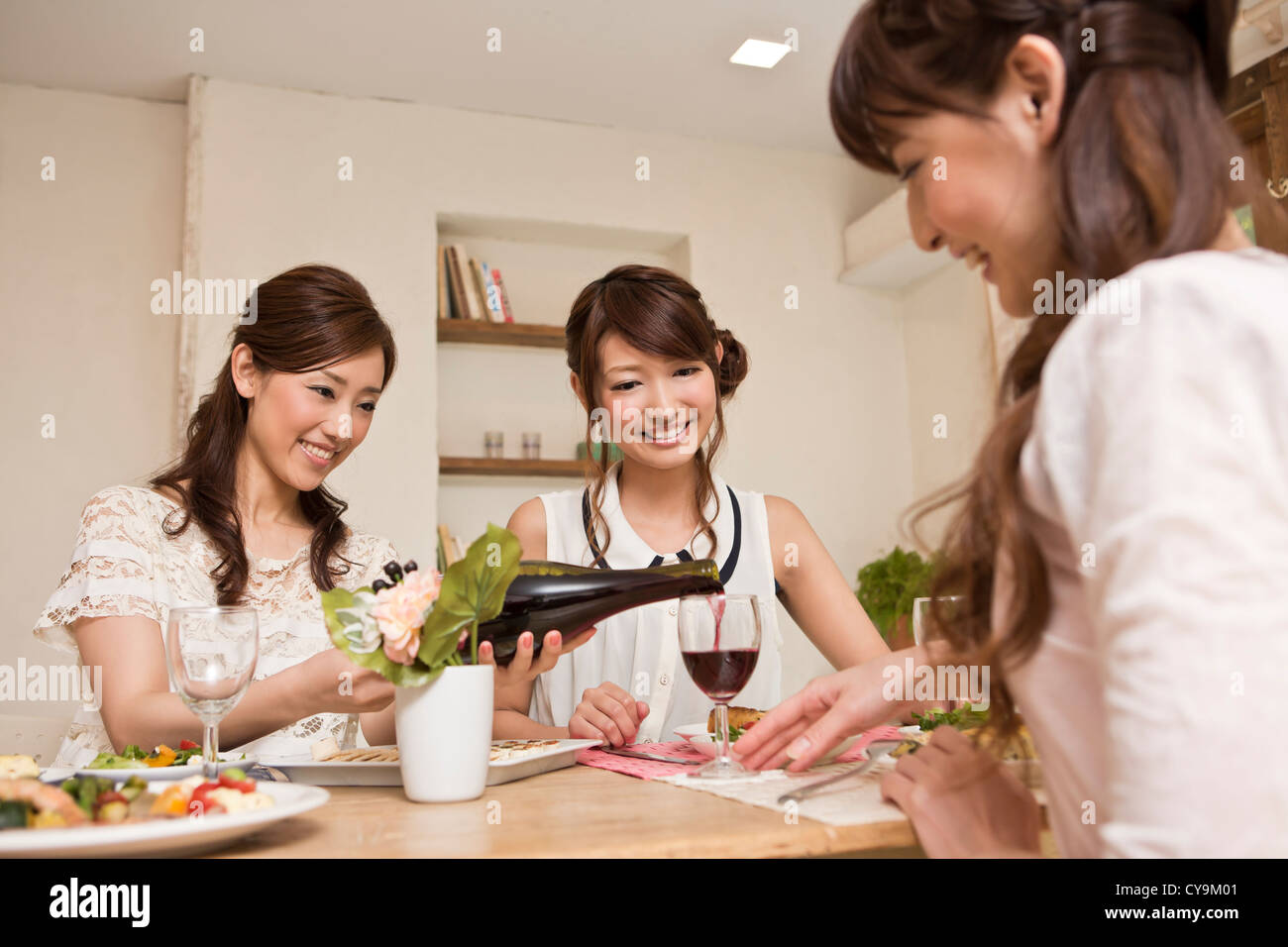 Three Young Women Enjoying Wine at Party Stock Photo