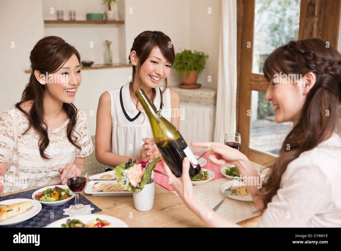 Three Young Women Enjoying Wine at Party Stock Photo