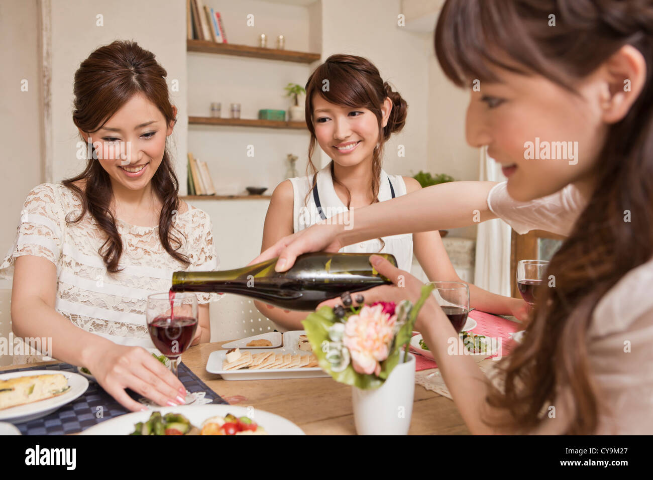 Three Young Women Enjoying Wine at Party Stock Photo
