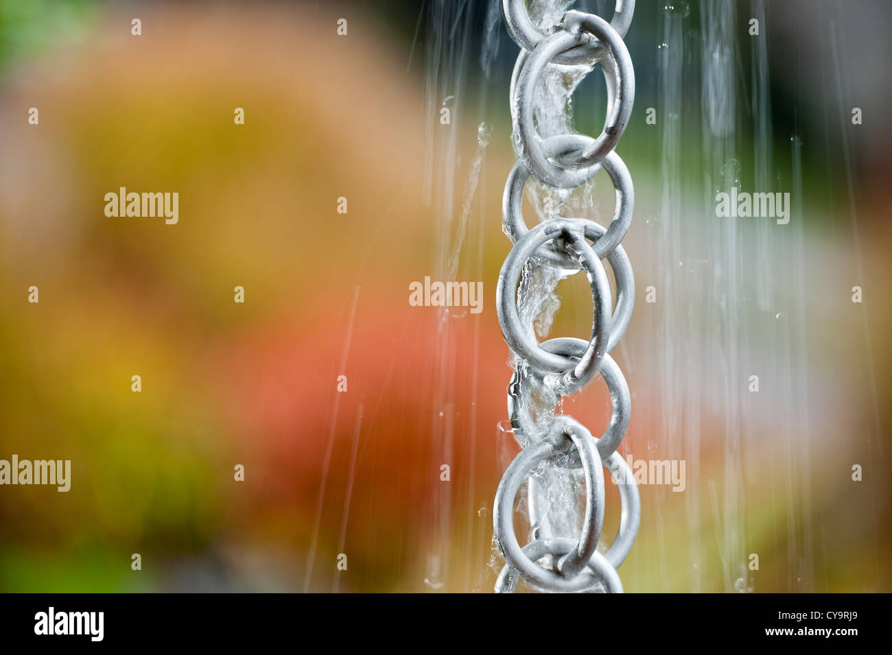 Rainwater from a household roof gushes down a rain chain during a storm.  Horizontal format, space for copy. Stock Photo
