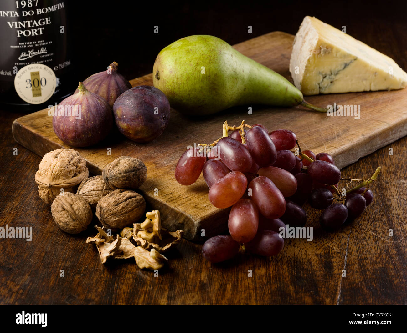Cheese board with Port wine, Pear, Grapes, Figs and Walnuts on a chopping board. Stock Photo