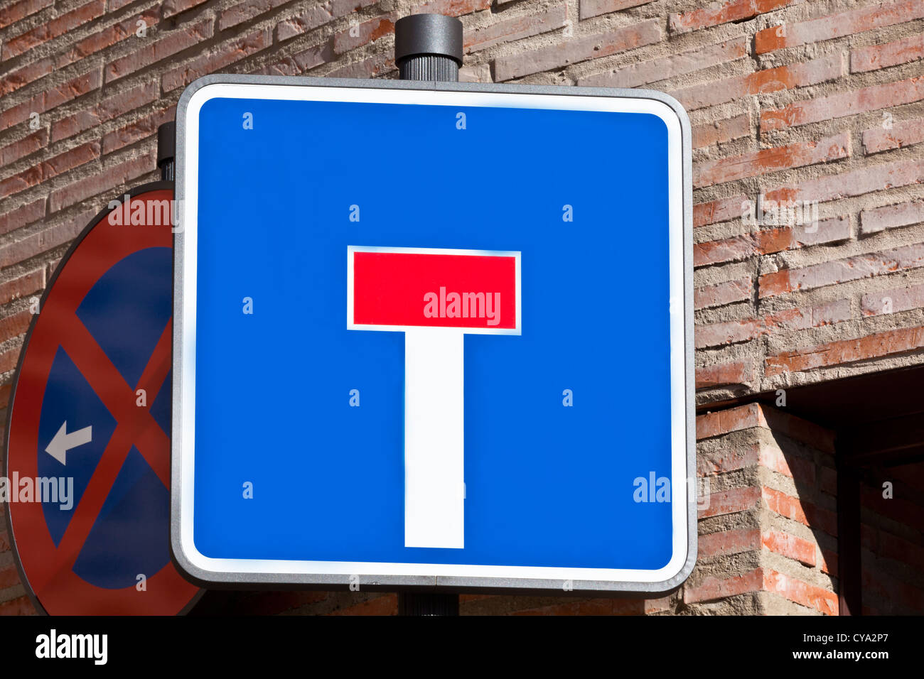 'Dead end' and 'Don't stop' road signs on the bick house wall Stock Photo