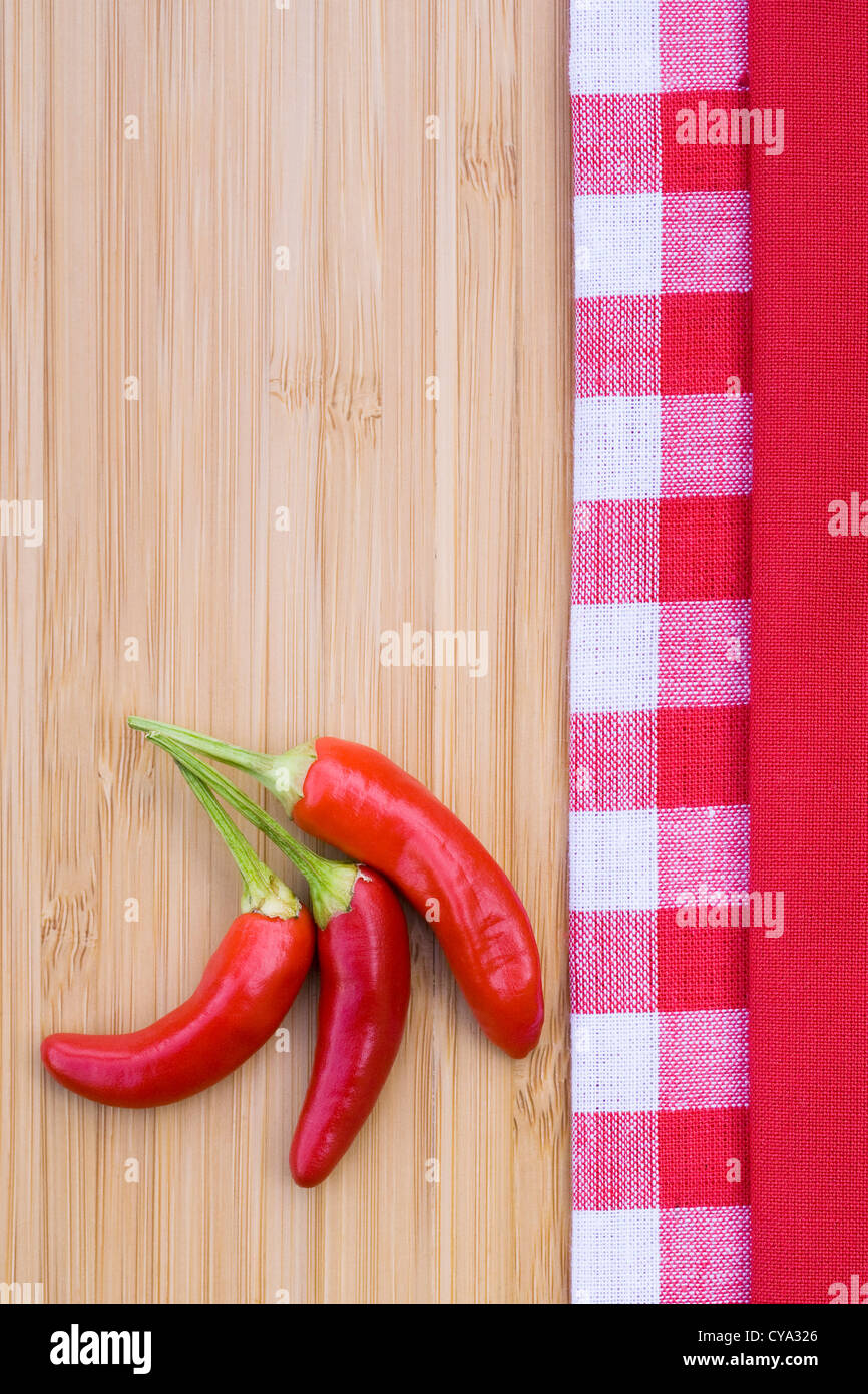 Capsicum annum 'Superchili'. Three chili peppers on a bamboo board. Stock Photo
