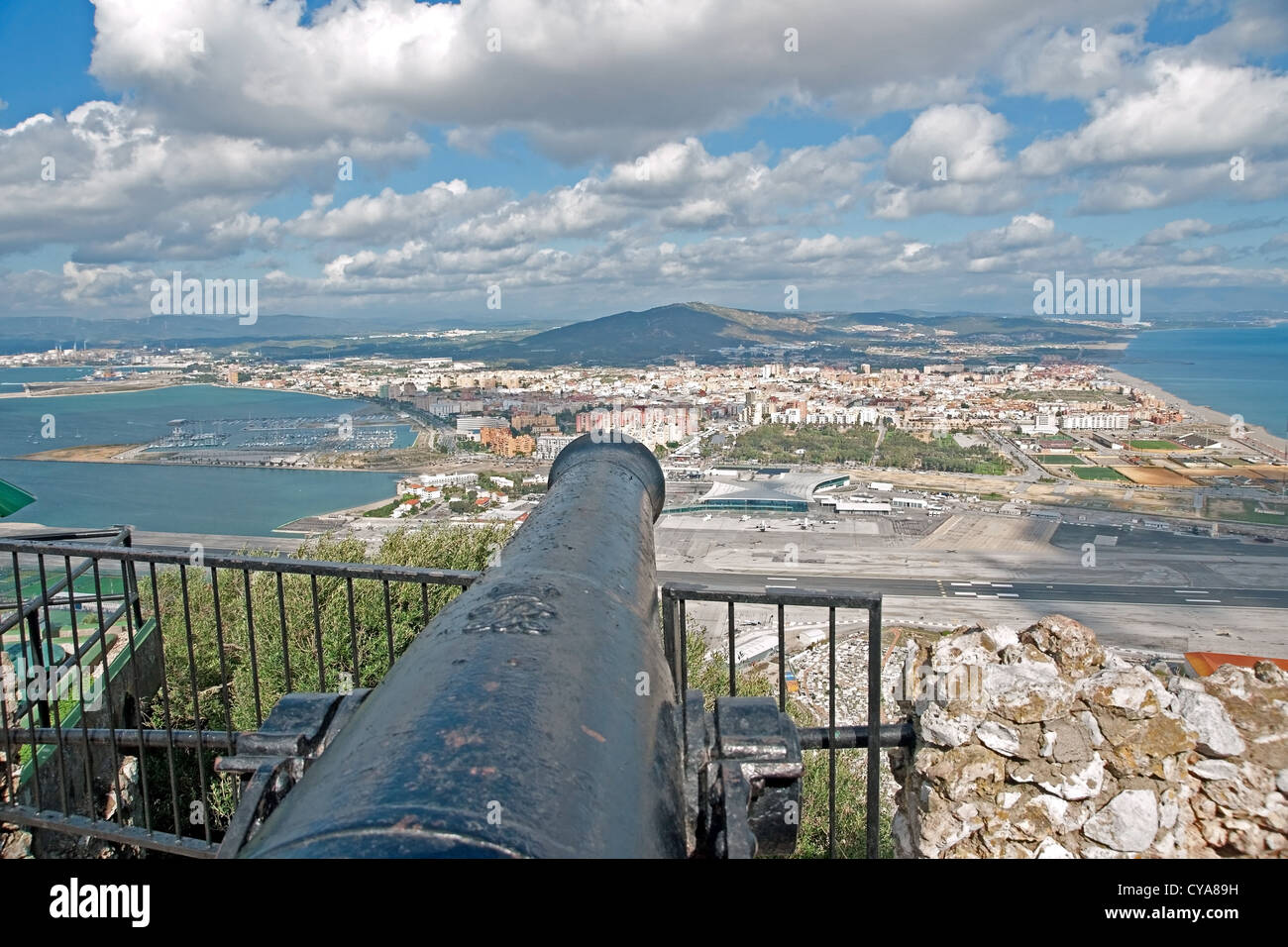 An old cannon looks out over Spain from the Rock of Gibraltar . In the foreground lies Gibraltar Airport and the border Stock Photo