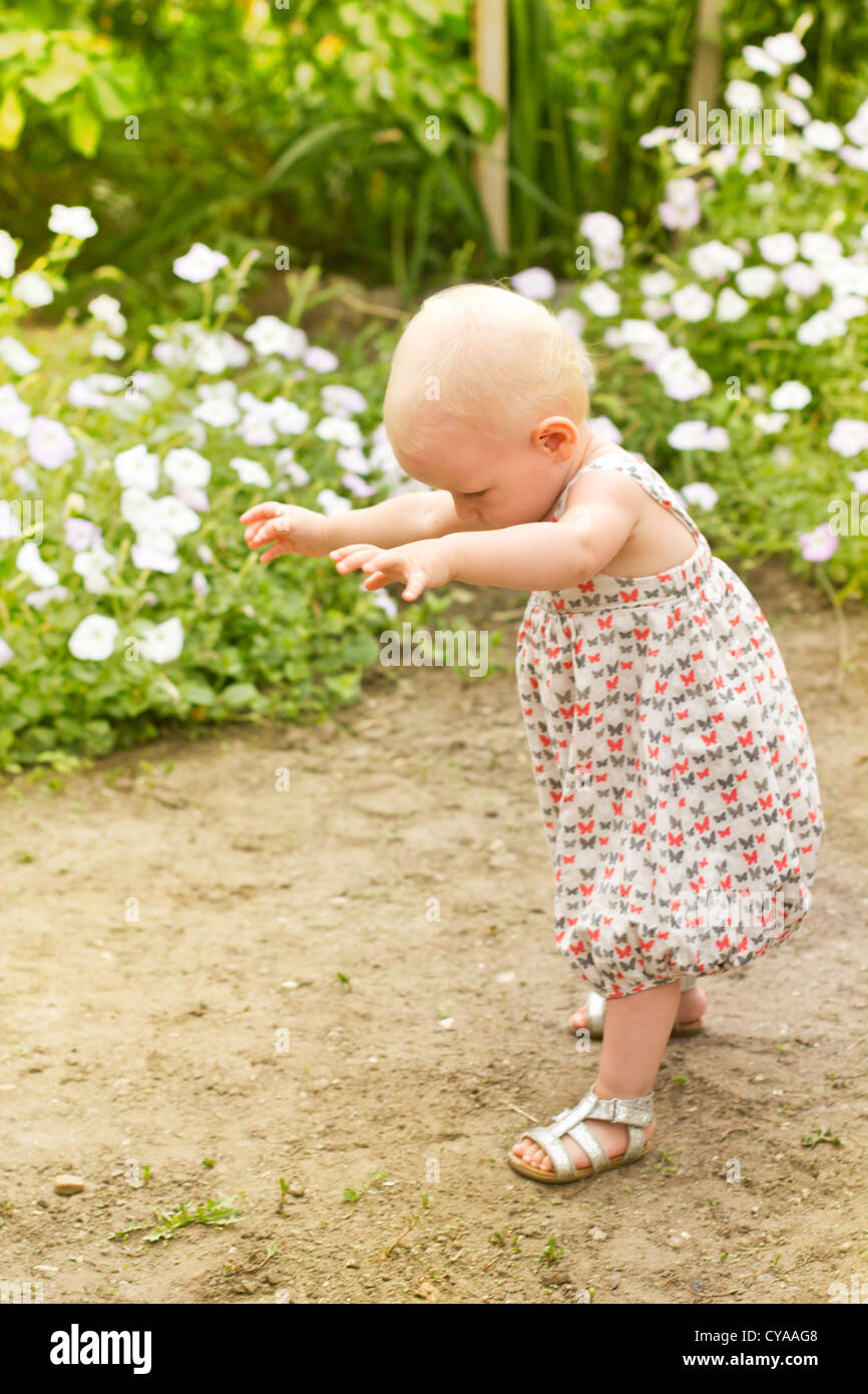 baby-girl-one-year-old-making-her-first-step-in-the-park-stock-photo