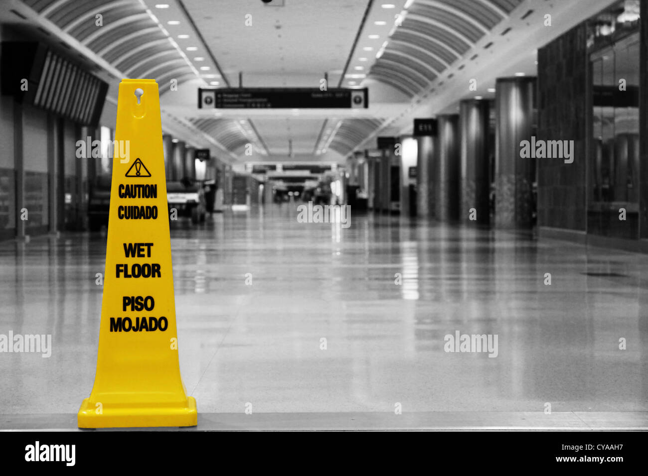 A yellow 'wet floor sign'' in an empty airport terminal at  Atlanta airport, which is the busiest airport in the world. Stock Photo