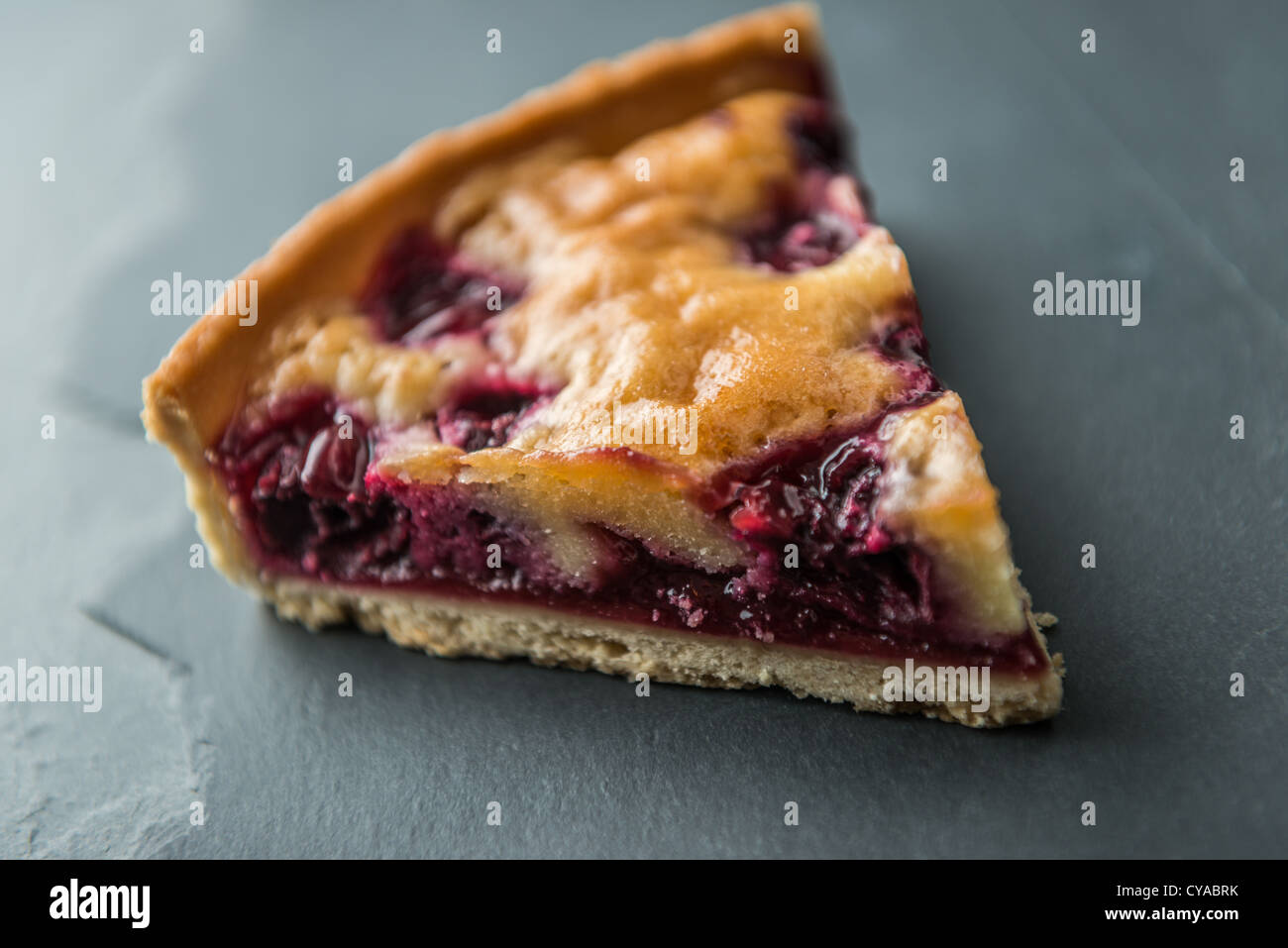 A slice of cherry tart dessert shot on a natural slate surface Stock Photo