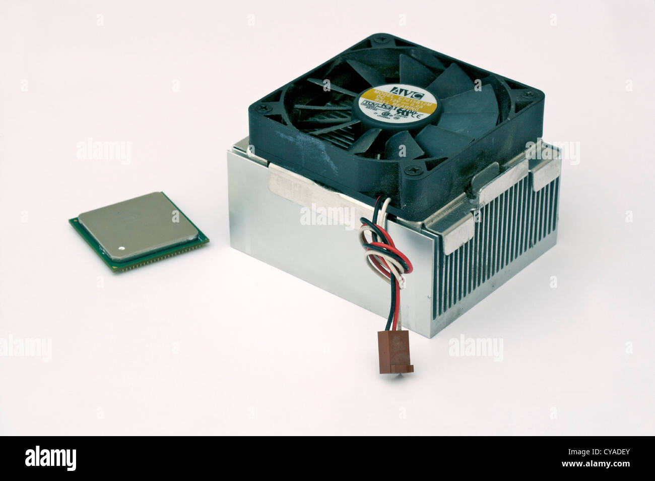 A PC central processor unit (CPU) chip and its heat sink with cooling fan standing on a plain background Stock Photo