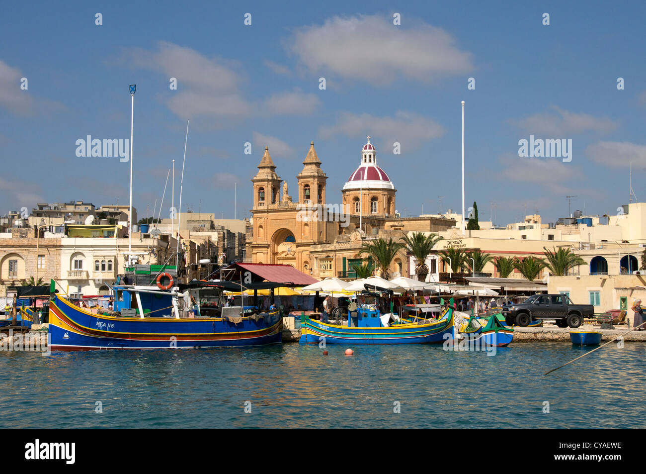 Fishing boats and church Marsaxlokk Port Malta Stock Photo