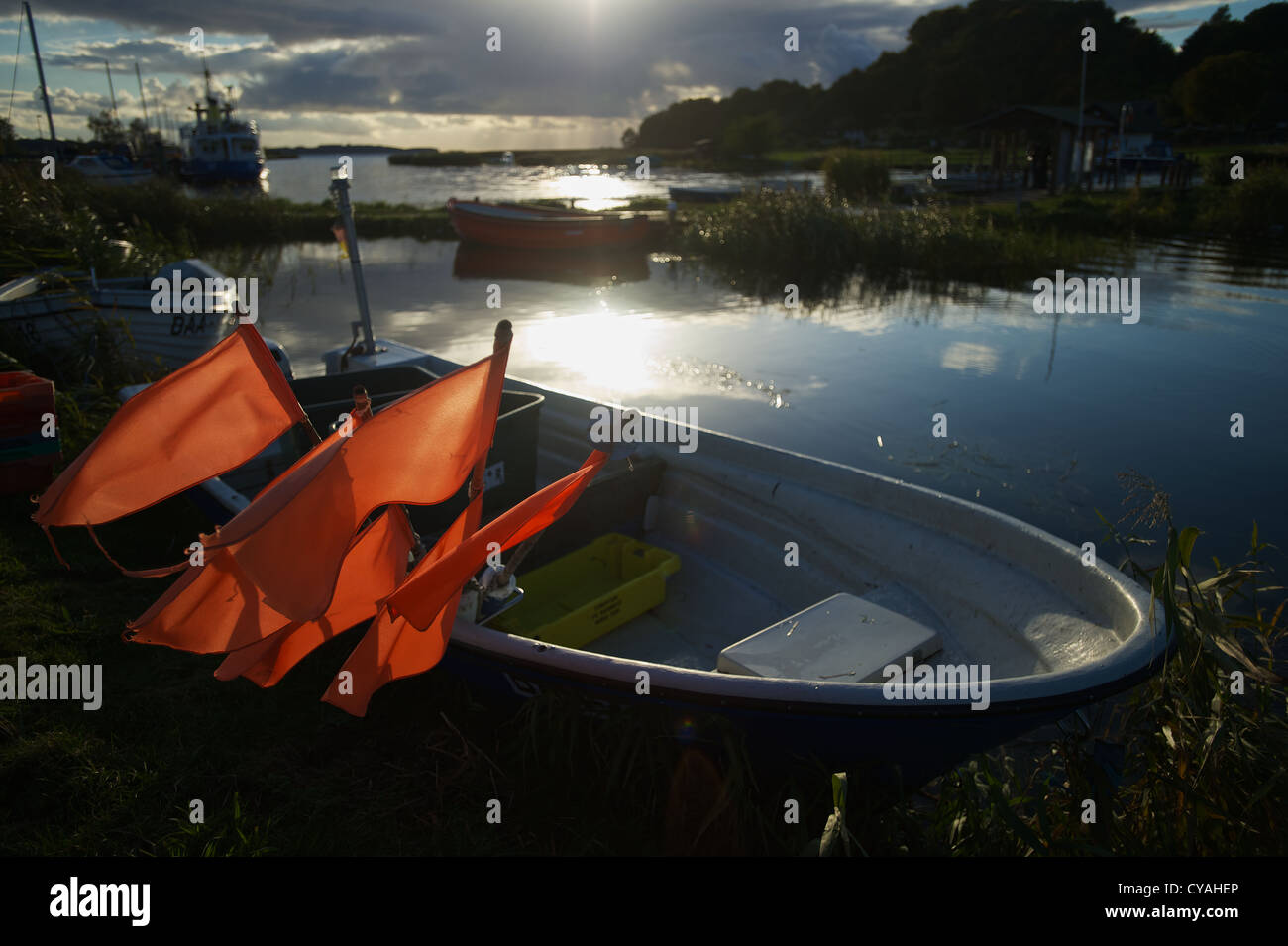 Fishing boat in the small port of Baabe on the Island of Rügen. Orange flags in the boat are illuminated by the sun from behind Stock Photo