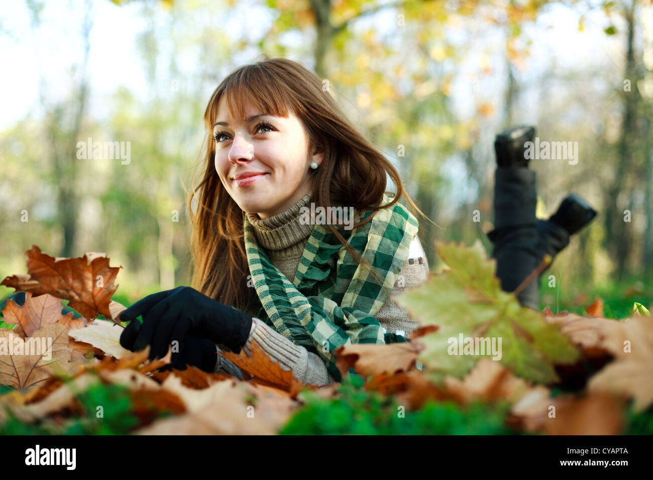 Happy girl lying on yellow leaves outdoors in autumn park Stock Photo ...