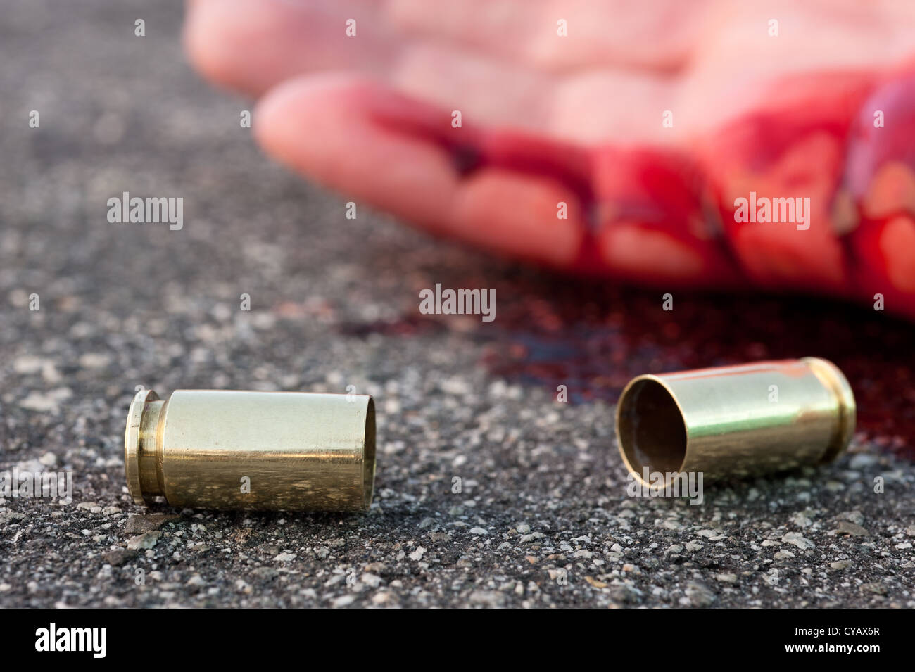 A man shot in the streets with the bullet casing laying next to a bloody hand. Stock Photo