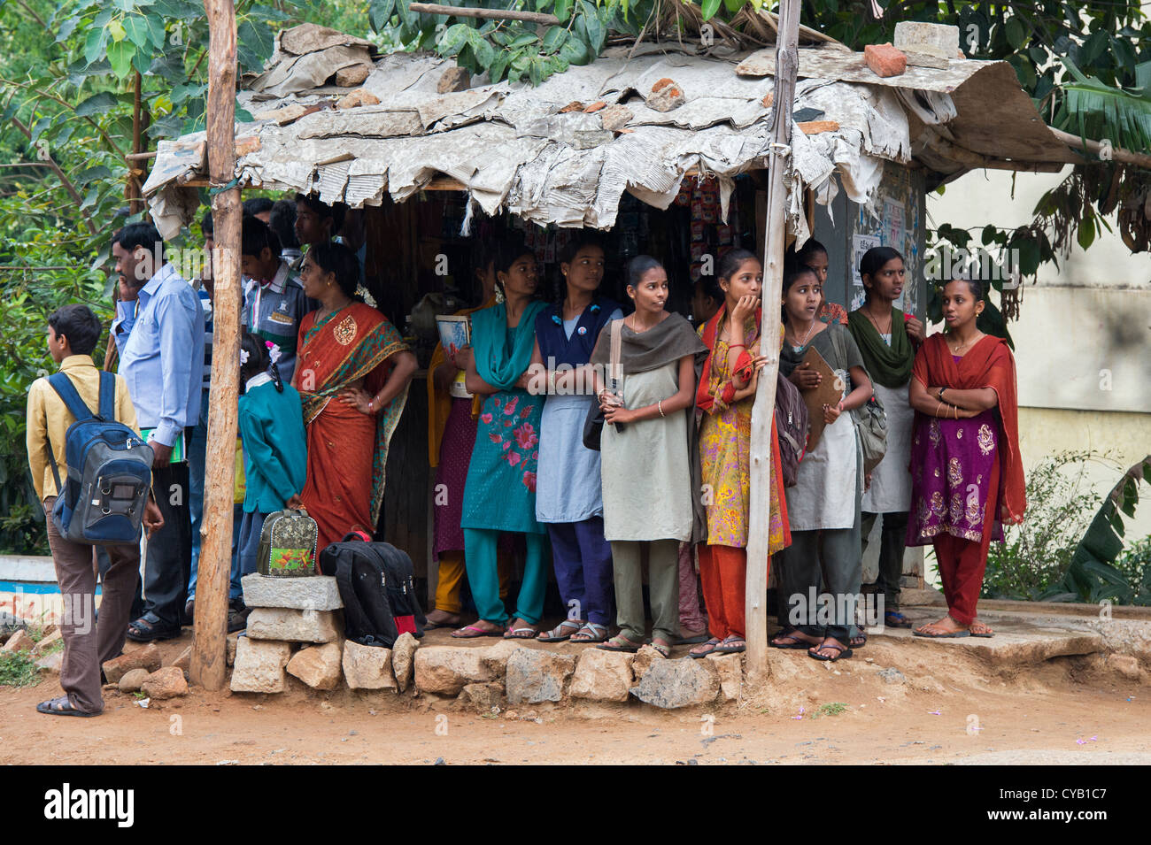 Group of Indian school girls sheltering from the rain whilst waiting for a bus. Andhra Pradesh, India Stock Photo