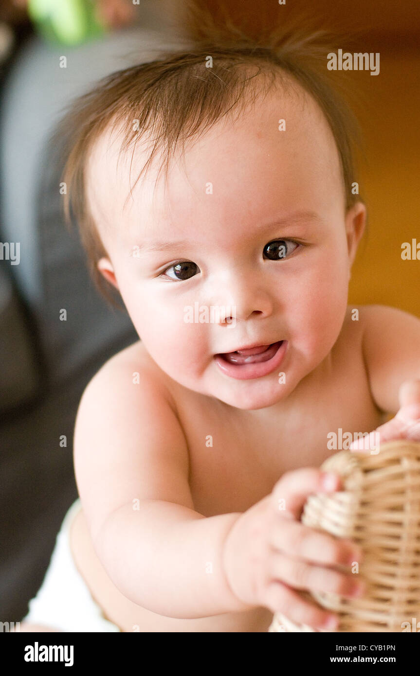 Ten month old baby pulling himself up on a rattan chair Stock Photo Alamy
