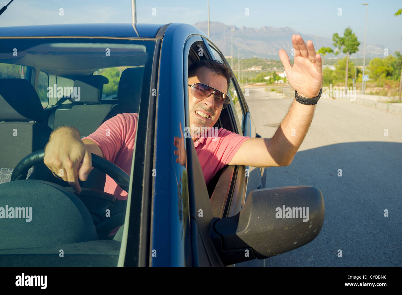 Driver hanging out of his car window gesticulating Stock Photo - Alamy