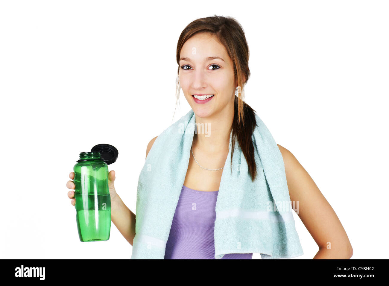 Cute, healthy and sporty young woman with towell on shoulders drinking water after working out, yoga or other exercise. Stock Photo