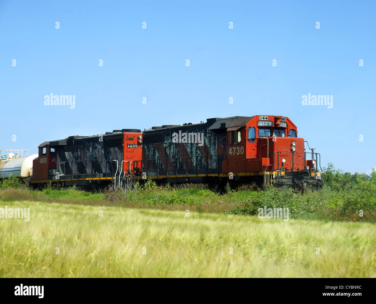Two old freight or cargo locomotives going through farmland or prairies to deliver products and merchandises. Stock Photo