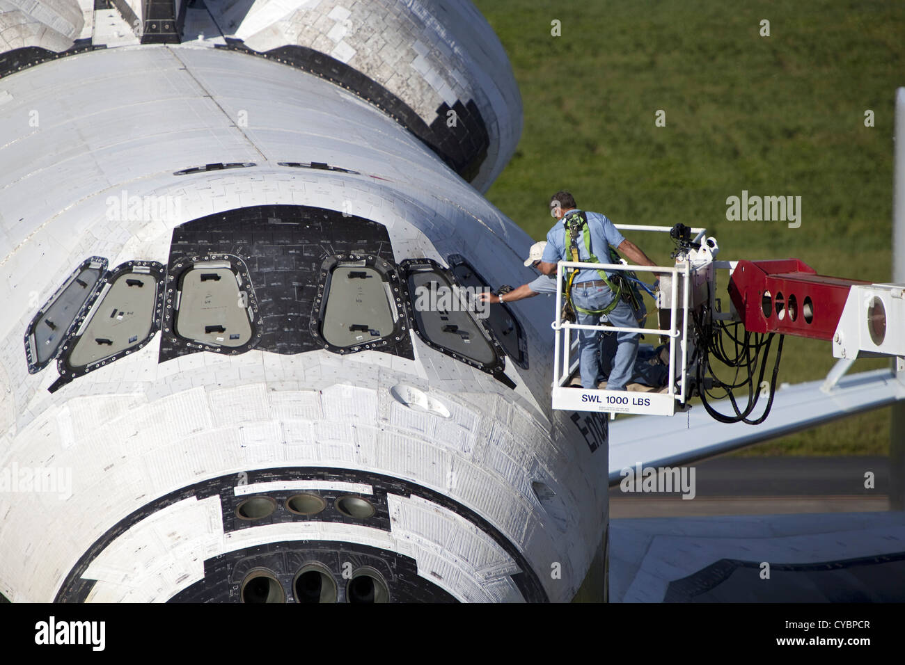United Space Alliance technicians uncover the cockpit windows on space shuttle Endeavour at the Shuttle Landing Facility at NASA's Kennedy Space Center September 16, 2012 in Florida. Endeavour is balanced and secured atop NASA's Shuttle Carrier Aircraft. The Shuttle Carrier Aircraft is a modified 747 jetliner that will fly Endeavour to Los Angeles where it will be placed on public display at the California Science Center. Stock Photo