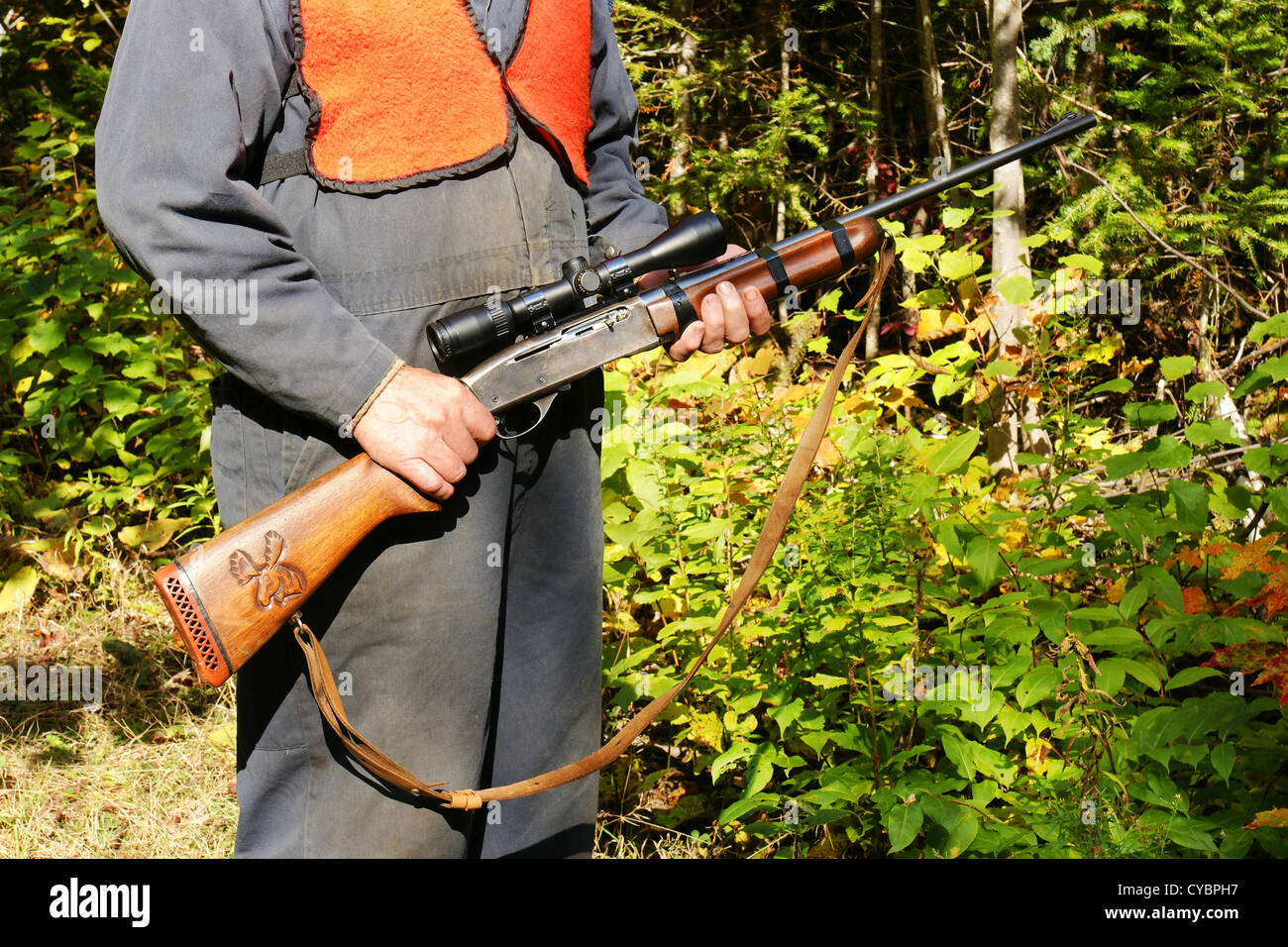 Man hunter with riffle in his hands, autumn forest behind Stock Photo