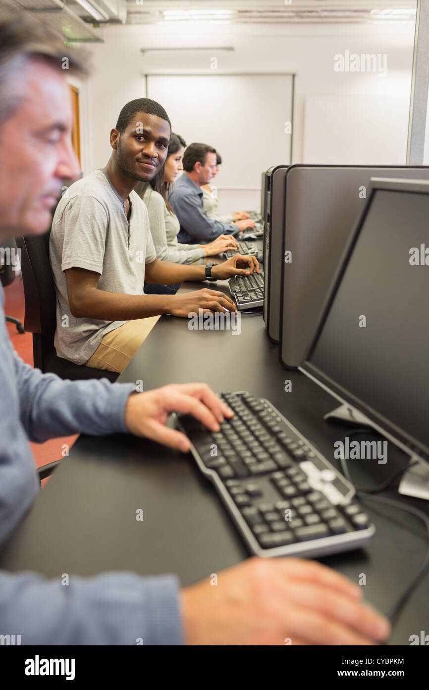 Smiling young man at computer class Stock Photo - Alamy