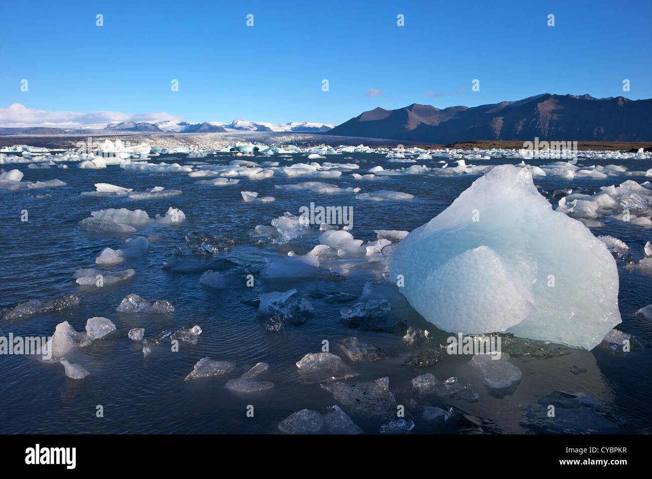 Icebergs on a glacial lake at Jokulsarlon with snow on the massive icecap of Vatnajokull behind, Iceland Stock Photo
