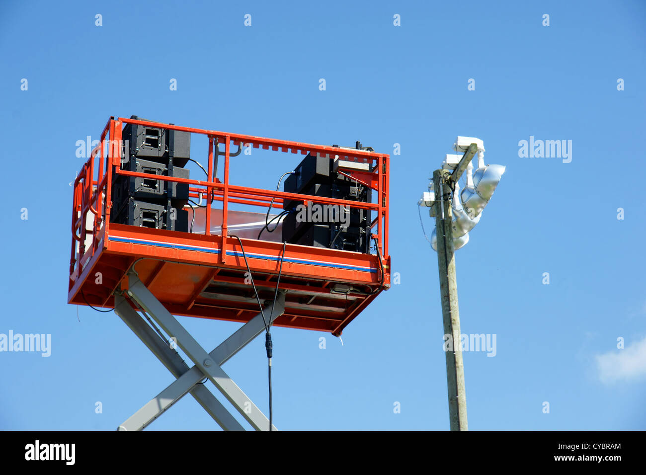 Stack of speaker equipment high in the sky on lift platform ready for outdoor concert in the park, beside lighting. Stock Photo