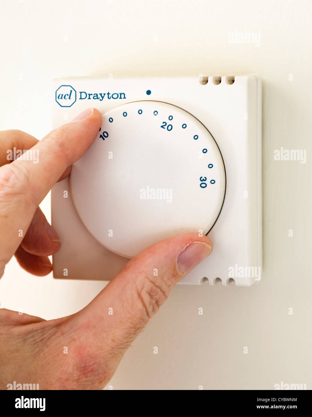 Turning down a central heating thermostat Stock Photo