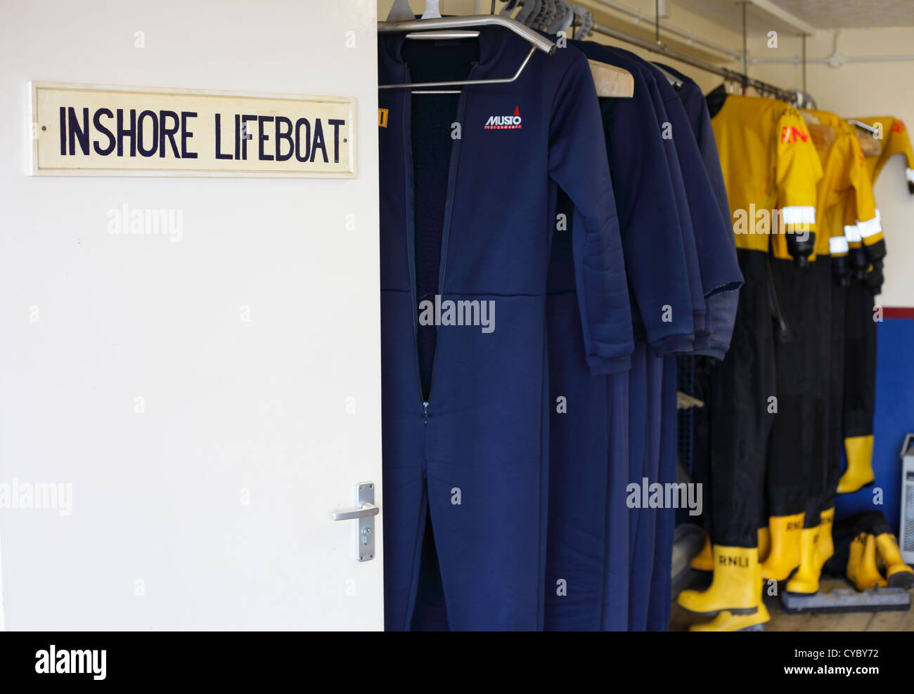 RNLI protective clothing hanging up in lifeboat house. Stock Photo