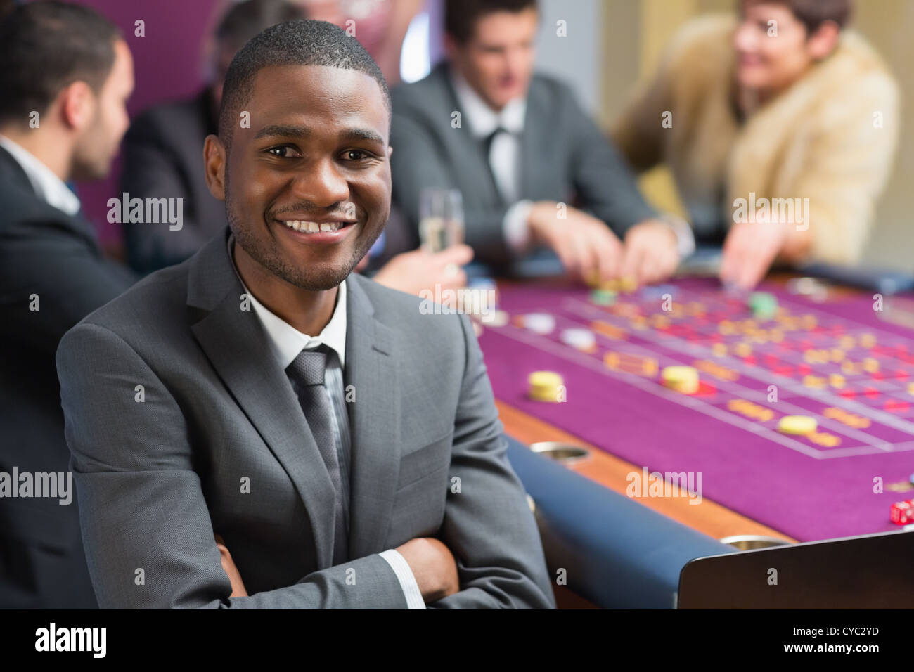 Smiling man sitting arms crossed at roulette table Stock Photo Alamy