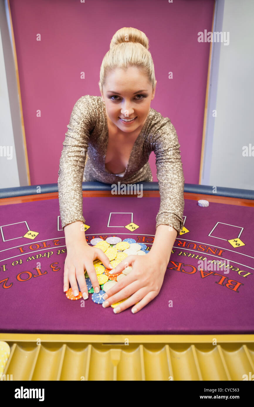 Smiling woman grabbing chips in a casino Stock Photo