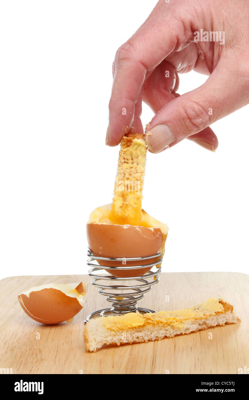 Hand dipping a toast soldier into a soft boiled egg Stock Photo