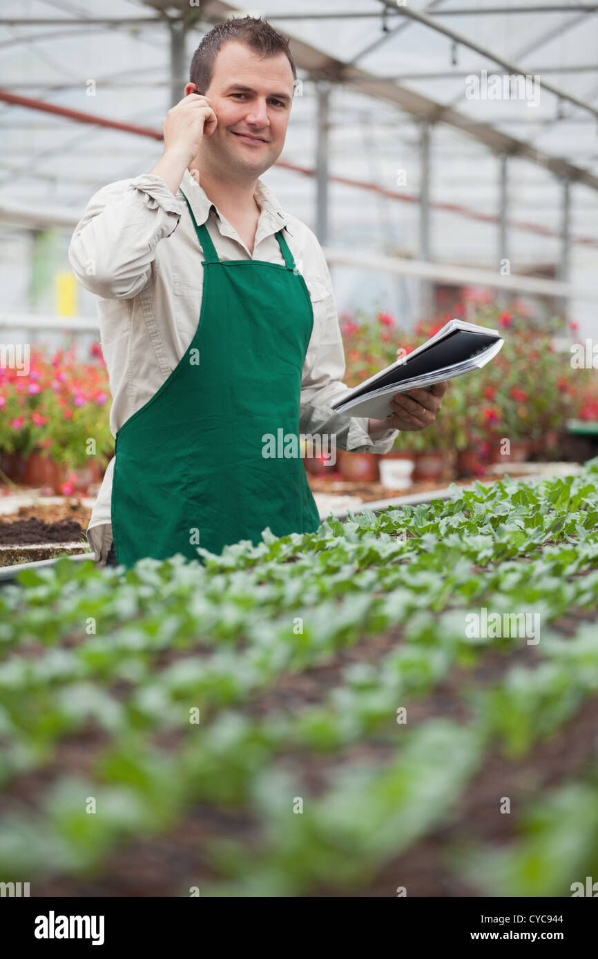 Smiling man on the phone and taking notes in greenhouse Stock Photo